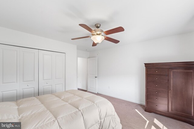 bedroom with ceiling fan, a closet, and light carpet