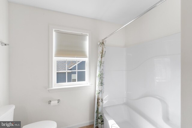 bathroom featuring toilet and shower / bath combination with curtain