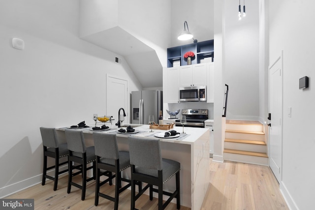 kitchen with a kitchen bar, light wood-type flooring, sink, and appliances with stainless steel finishes