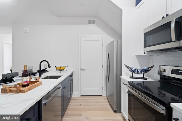 kitchen featuring appliances with stainless steel finishes, light stone counters, white cabinetry, and sink