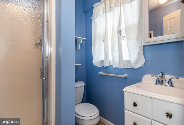 full bath featuring a stall shower, toilet, vanity, and baseboards