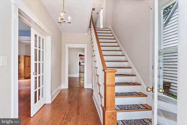 entrance foyer with wood finished floors, french doors, baseboards, a chandelier, and stairs