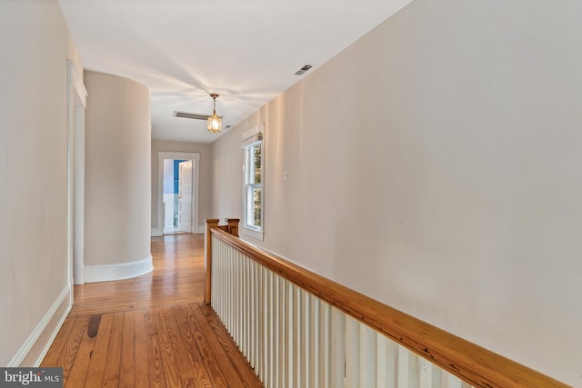 hallway with an inviting chandelier and light hardwood / wood-style floors