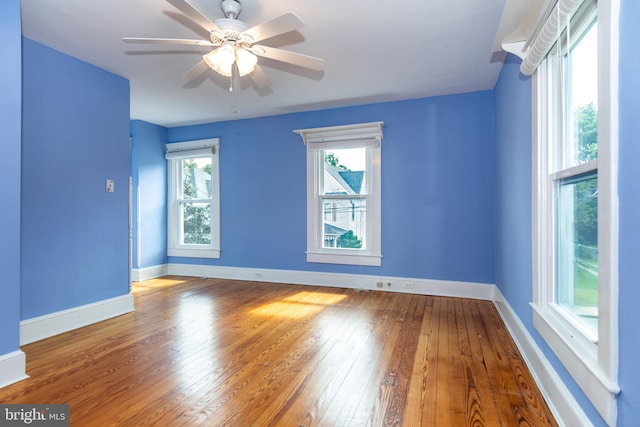 unfurnished room with baseboards, a ceiling fan, and hardwood / wood-style flooring