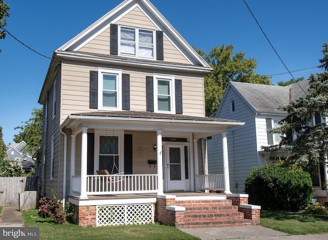 american foursquare style home with a porch and fence