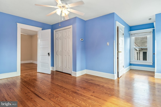 unfurnished bedroom featuring ceiling fan, a closet, baseboards, and wood finished floors