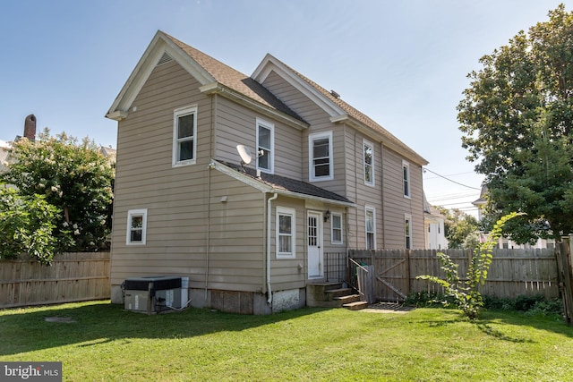 rear view of house featuring cooling unit, a yard, a fenced backyard, and entry steps