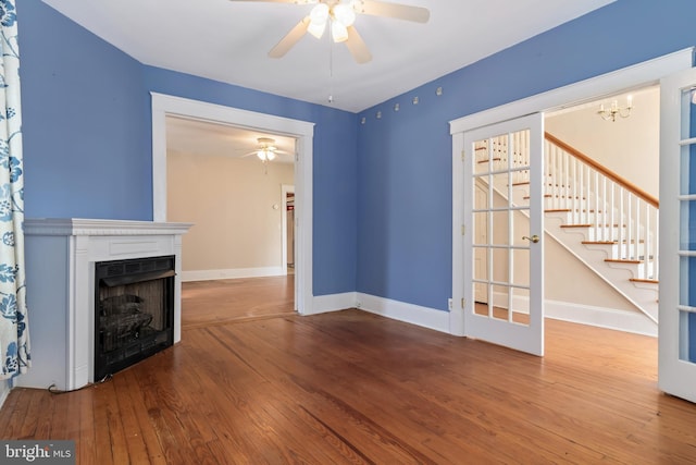 unfurnished living room featuring hardwood / wood-style floors, stairway, a fireplace, and baseboards