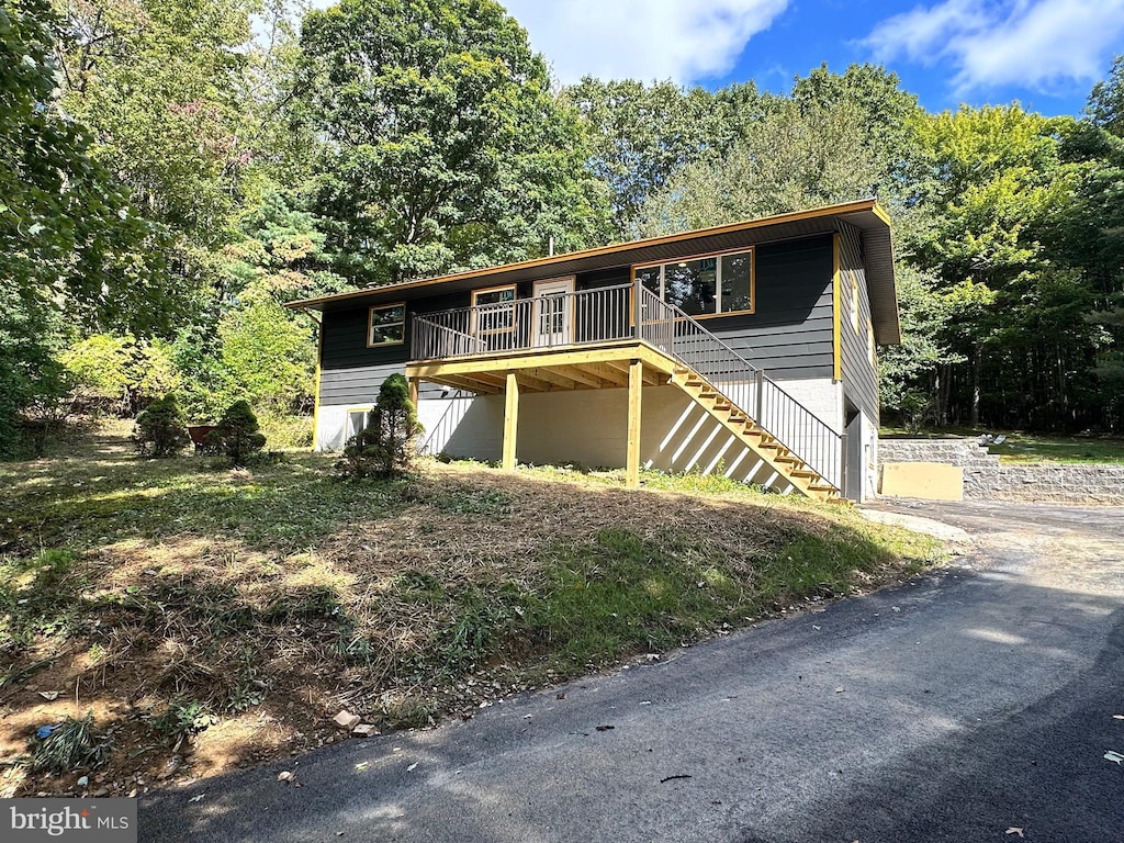 view of front of house featuring stairway, a forest view, and a deck