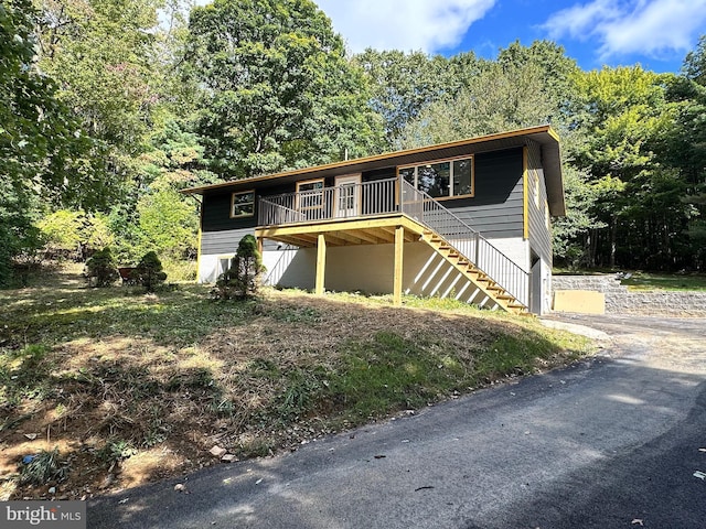 view of front of house featuring stairway, a forest view, and a deck