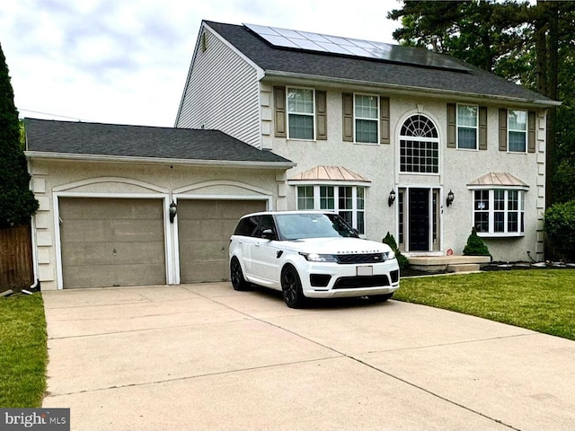 colonial house with a front yard, solar panels, and a garage