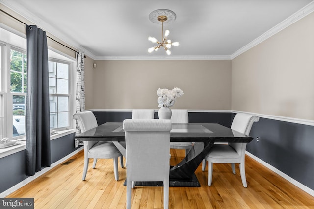 dining room with light wood-type flooring, crown molding, and an inviting chandelier