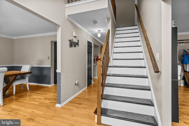 staircase featuring wood-type flooring and crown molding