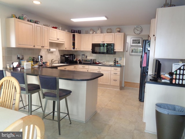 kitchen featuring a kitchen breakfast bar, kitchen peninsula, black appliances, and backsplash