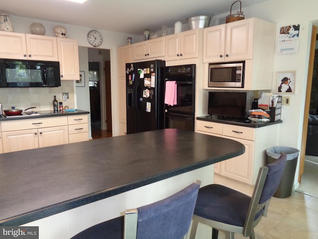 kitchen featuring black appliances, a kitchen breakfast bar, and tasteful backsplash