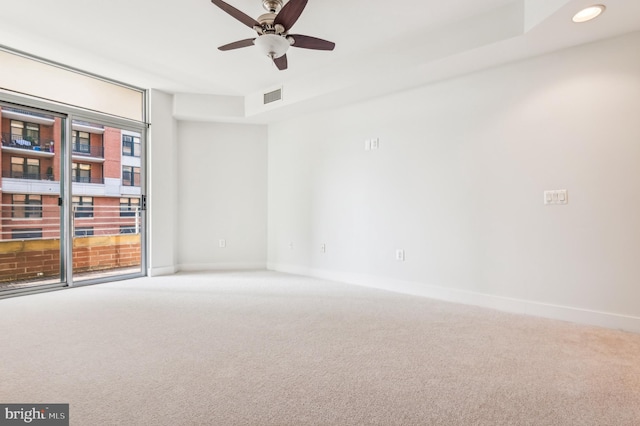 carpeted empty room with visible vents, ceiling fan, and baseboards