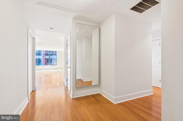 hall with light wood finished floors, visible vents, and baseboards