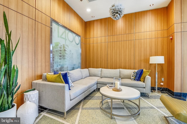 living area featuring speckled floor, wood walls, and recessed lighting