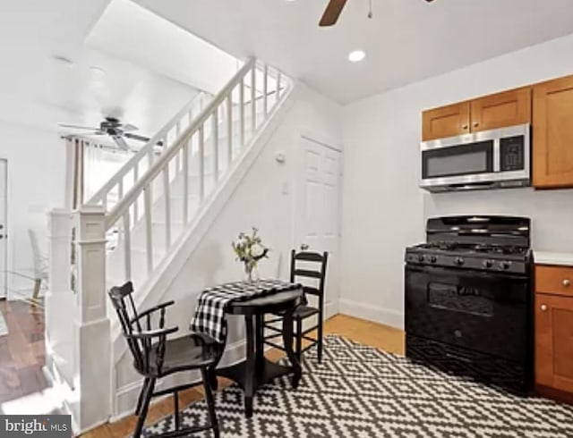 kitchen featuring hardwood / wood-style floors, black gas stove, and ceiling fan