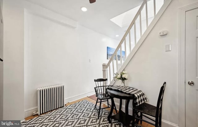 dining room featuring wood finished floors, recessed lighting, radiator, a skylight, and baseboards