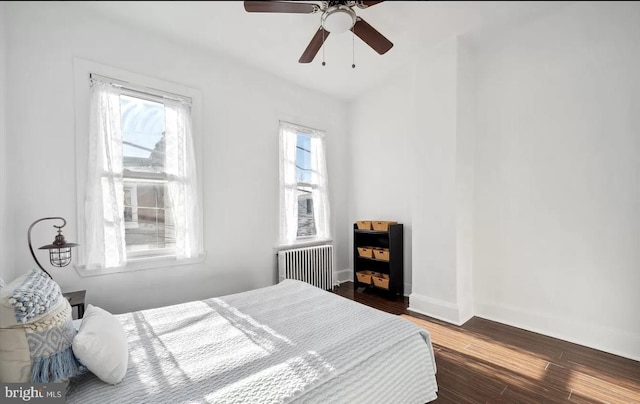 bedroom with a ceiling fan, radiator heating unit, wood finished floors, and baseboards