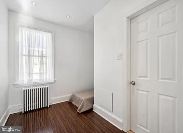 unfurnished bedroom featuring dark wood-style floors, radiator, and baseboards