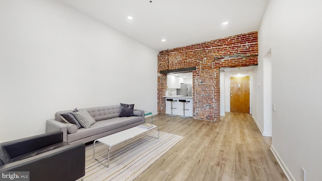 unfurnished living room with light wood-type flooring and brick wall