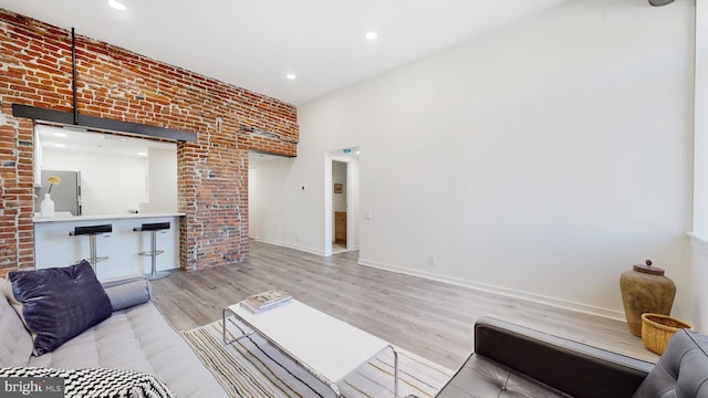 living room featuring light wood-type flooring and brick wall