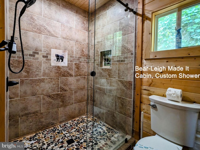 bathroom featuring toilet, an enclosed shower, and wooden walls