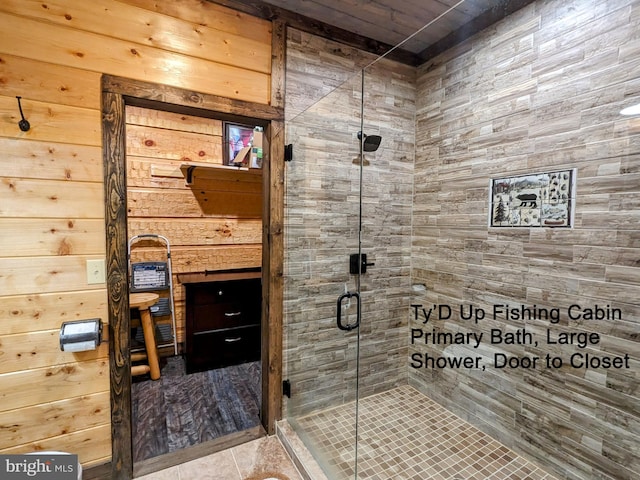 bathroom featuring a shower with door, tile patterned floors, and wooden walls