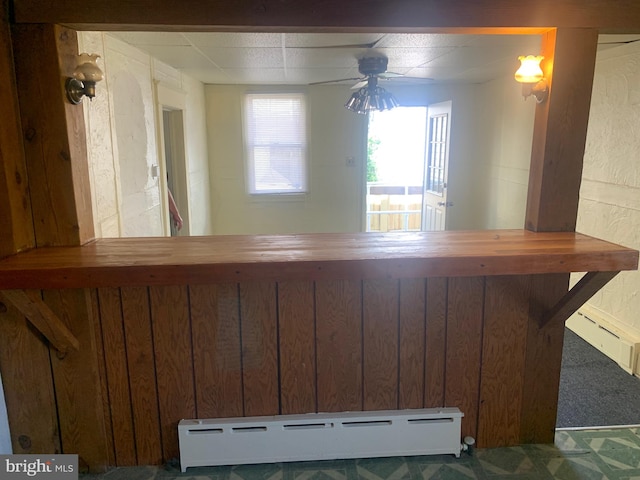 bar with wood walls, ceiling fan, and baseboard heating