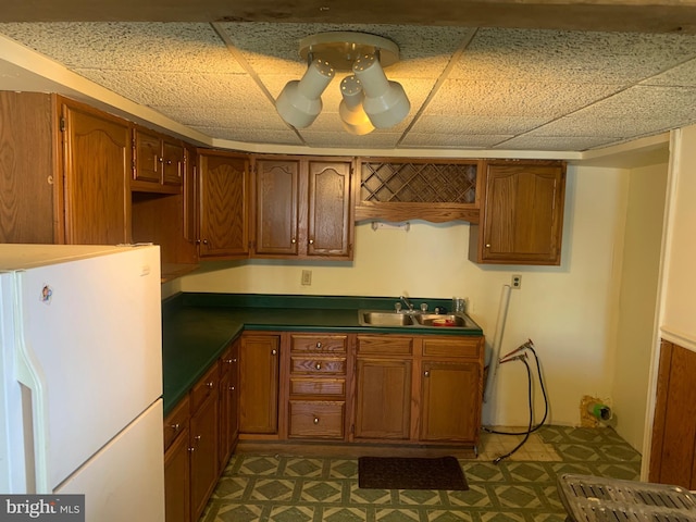 kitchen featuring a sink, brown cabinets, and freestanding refrigerator