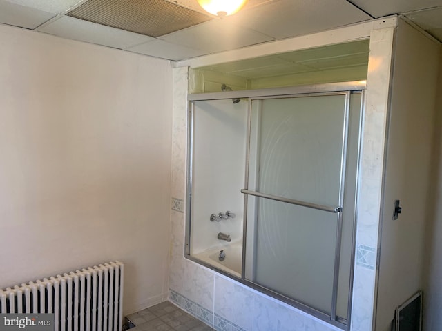 bathroom with tile patterned floors, enclosed tub / shower combo, and radiator