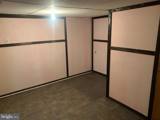 finished basement featuring tile patterned floors, a drop ceiling, and baseboards