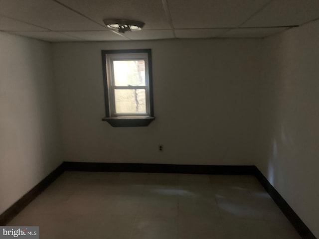 spare room featuring a paneled ceiling and baseboards