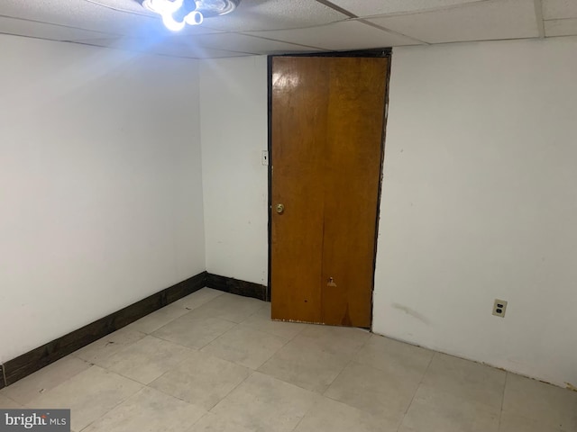 unfurnished room with light tile patterned floors, a paneled ceiling, and baseboards