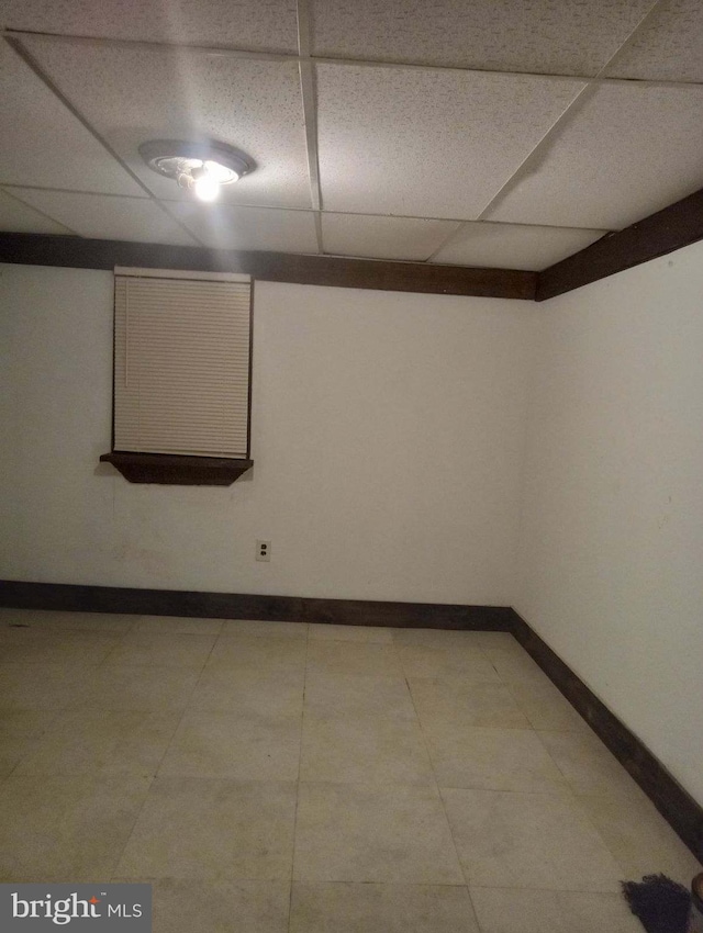 finished basement featuring light tile patterned floors, baseboards, and a paneled ceiling