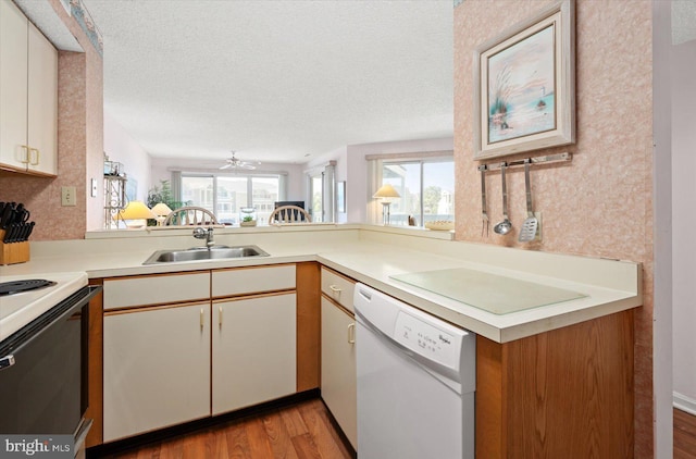 kitchen with light hardwood / wood-style floors, sink, white cabinetry, kitchen peninsula, and white appliances