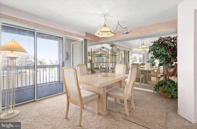 dining room with an inviting chandelier, a textured ceiling, and carpet