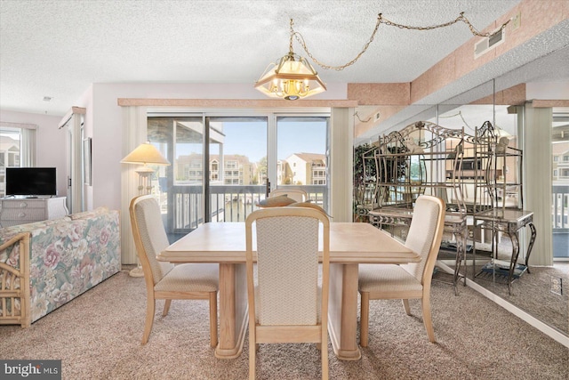 carpeted dining area with a notable chandelier and a textured ceiling