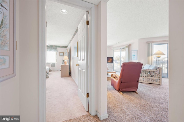 hallway featuring light carpet and a textured ceiling