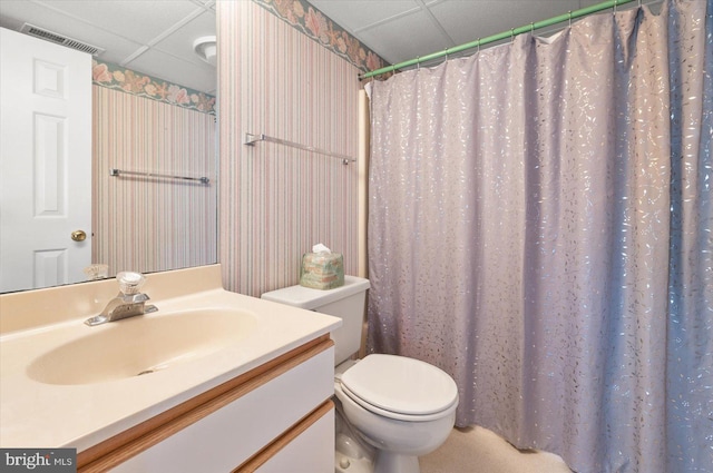 bathroom featuring walk in shower, a drop ceiling, vanity, and toilet