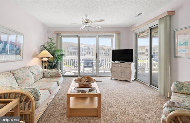 carpeted living room with ceiling fan and a textured ceiling