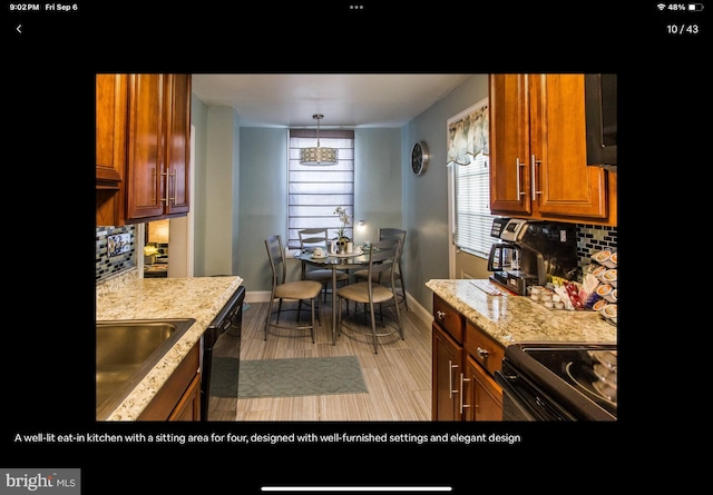 kitchen featuring backsplash, black appliances, sink, hanging light fixtures, and light hardwood / wood-style floors