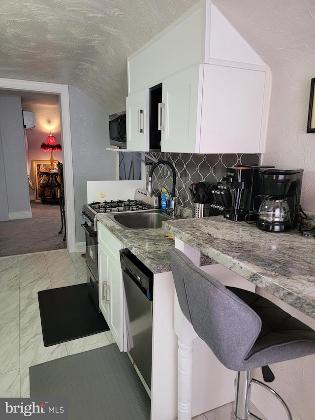 kitchen featuring white cabinets, stainless steel appliances, an AC wall unit, a kitchen bar, and tasteful backsplash