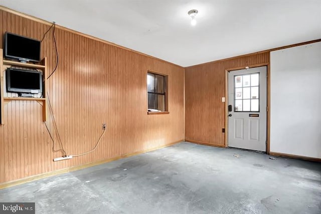 interior space with wood walls, concrete flooring, and baseboards