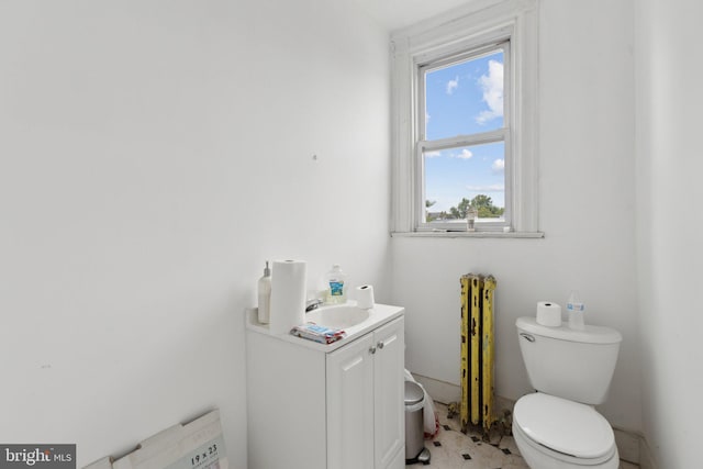 bathroom with toilet, plenty of natural light, radiator, and vanity