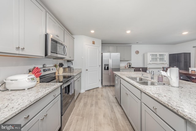 kitchen with light wood-type flooring, appliances with stainless steel finishes, gray cabinets, and sink