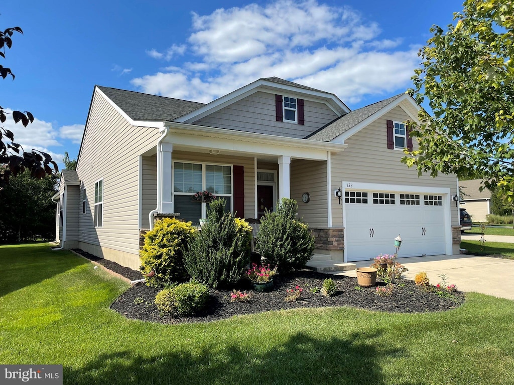 view of front facade featuring a garage, concrete driveway, a front lawn, and a shingled roof