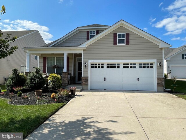 view of front facade featuring a garage, covered porch, and a front lawn